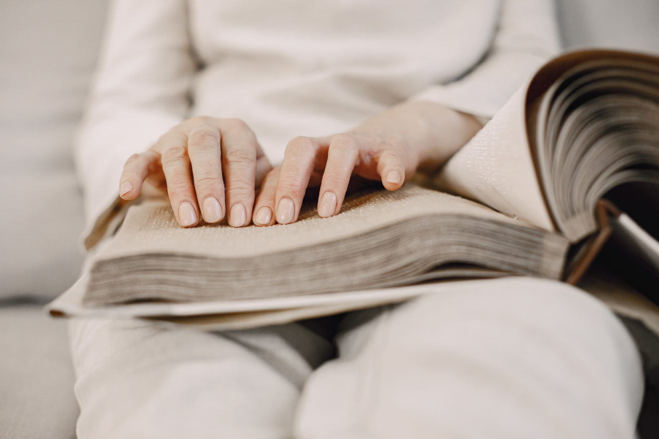 Mature woman read braille book on couch