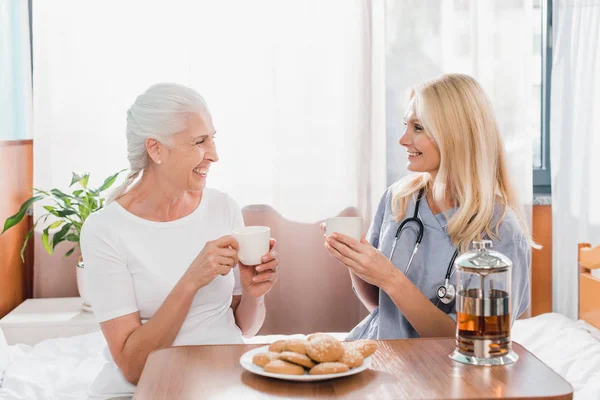 image d'une personne âgée qui prend le thé avec une aide soignante